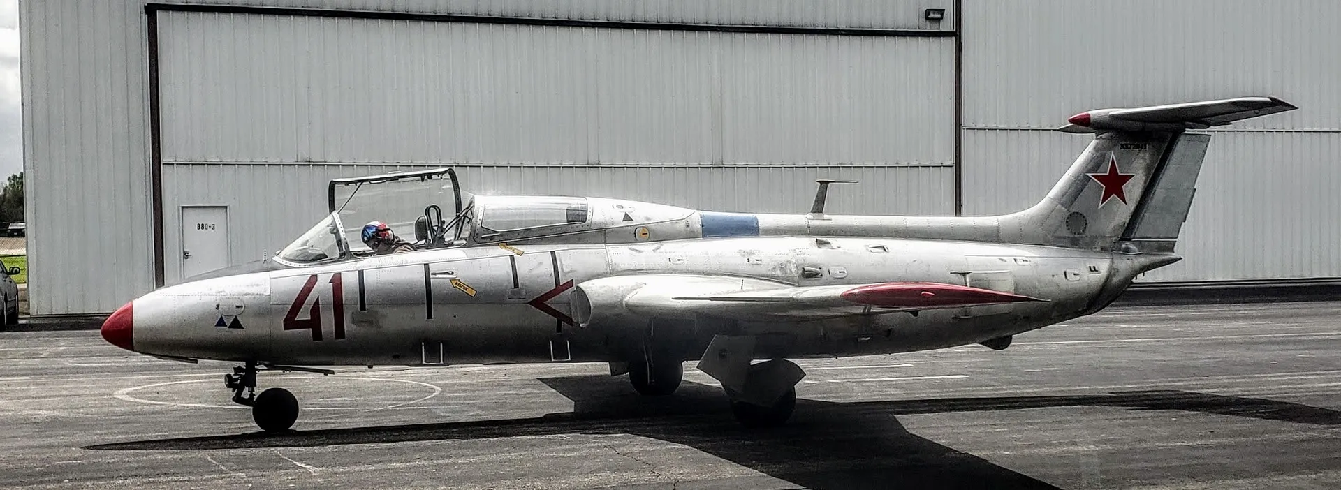 Silver Aero L-29 Delfín jet trainer, red number 41, with the pilot in the open cockpit